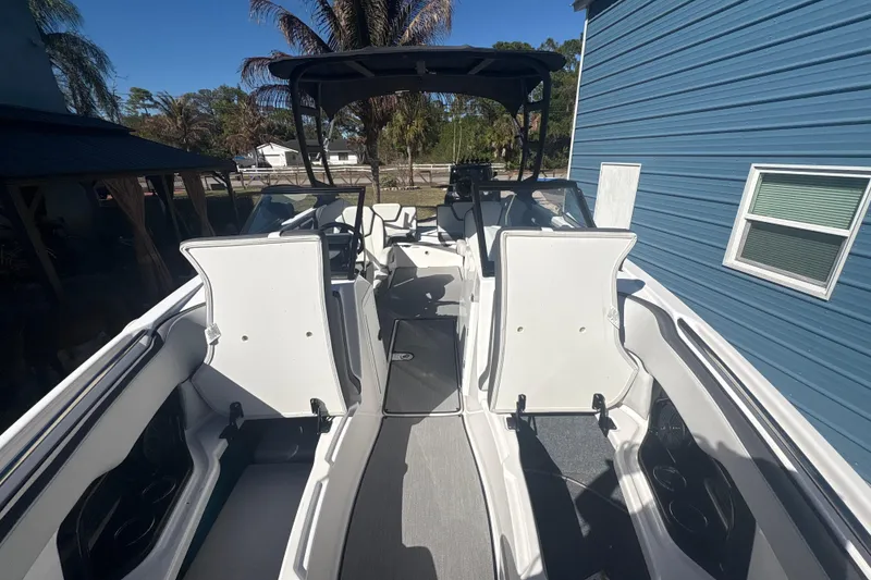 Slide: The Image of 2025 Yamaha Boats AR250 interior with gray seating, parked in a sunny driveway. - 17
