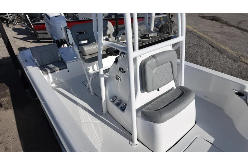 Slide: The Image of 2026 Blazer PureBay 2400 boat interior with gray seating and console, parked on pavement. - 8
