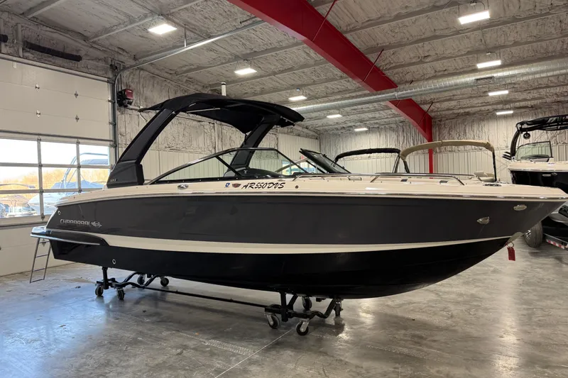 Slide: The Image of 2020 Chaparral 257 SSX boat in showroom, black and white exterior, indoor lighting. - 2