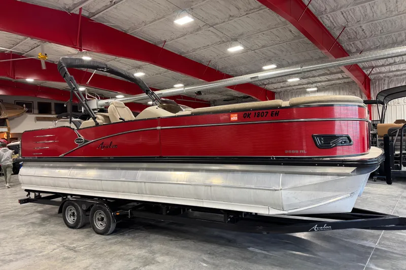 Slide: The Image of 2019 Avalon 2585 Catalina pontoon boat with red exterior in indoor showroom. - 1