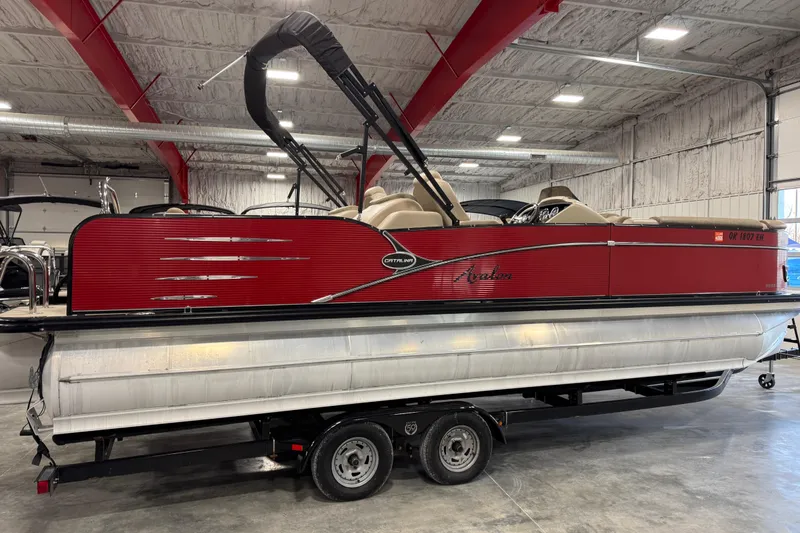Slide: The Image of 2019 Avalon 2585 Catalina pontoon boat in a warehouse, red exterior, on a trailer. - 3