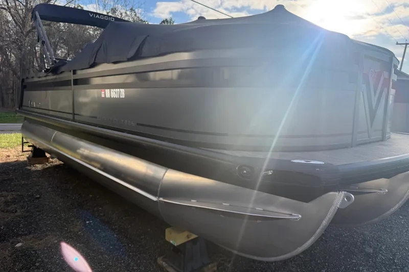 Slide: The Image of 2025 Viaggio Z22S pontoon boat with cover, parked outdoors in sunlight. - 56
