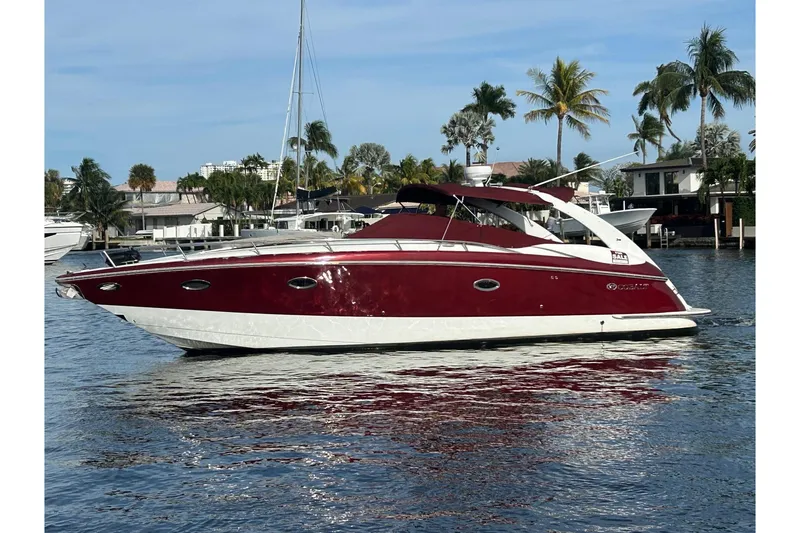 Slide: The Image of 2005 Cobolt 36 boat on water, red and white design, palm trees in background. - 0