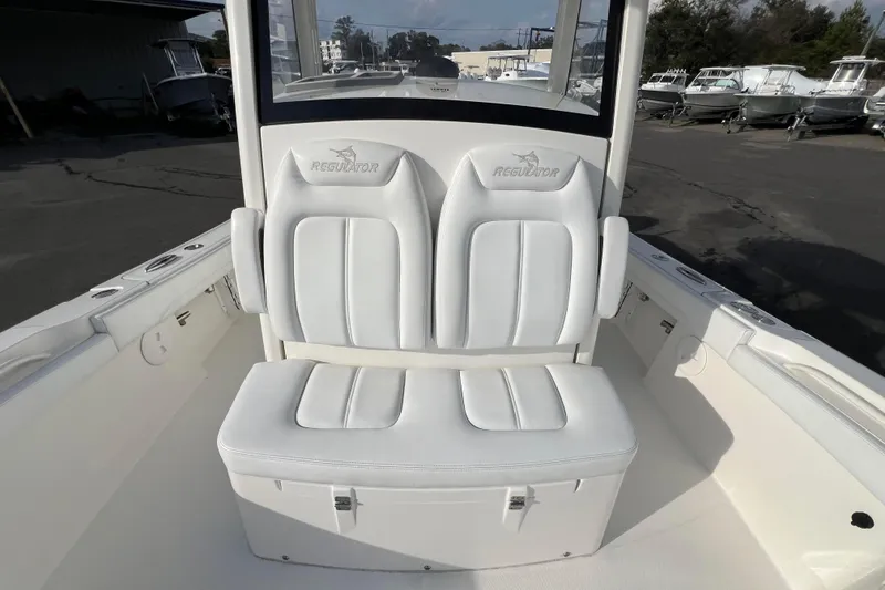 Slide: The Image of 2019 Regulator 26XO boat with white cushioned seating and storage compartment. - 13