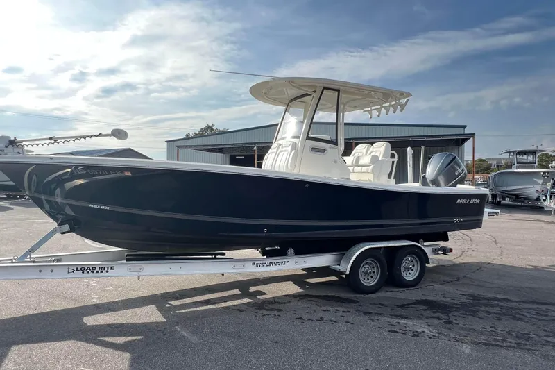 Slide: The Image of 2019 Regulator 26XO boat on trailer, parked outdoors under a cloudy sky. - 7