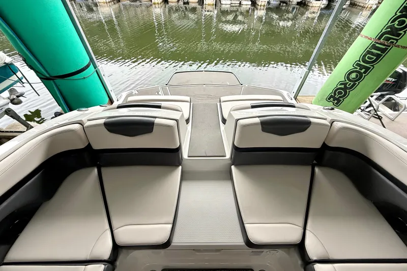Slide: The Image of 2018 Chaparral Vortex 2430 VRX boat interior with cushioned seating by the water. - 21
