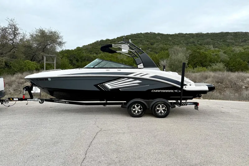 Slide: The Image of 2018 Chaparral Vortex 2430 VRX boat on trailer, parked on road with scenic background. - 9