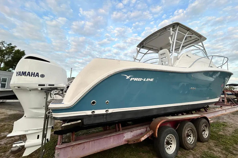 Slide: The Image of 2007 Pro-Line 32 Express boat with Yamaha engine on a trailer under a cloudy sky. - 16