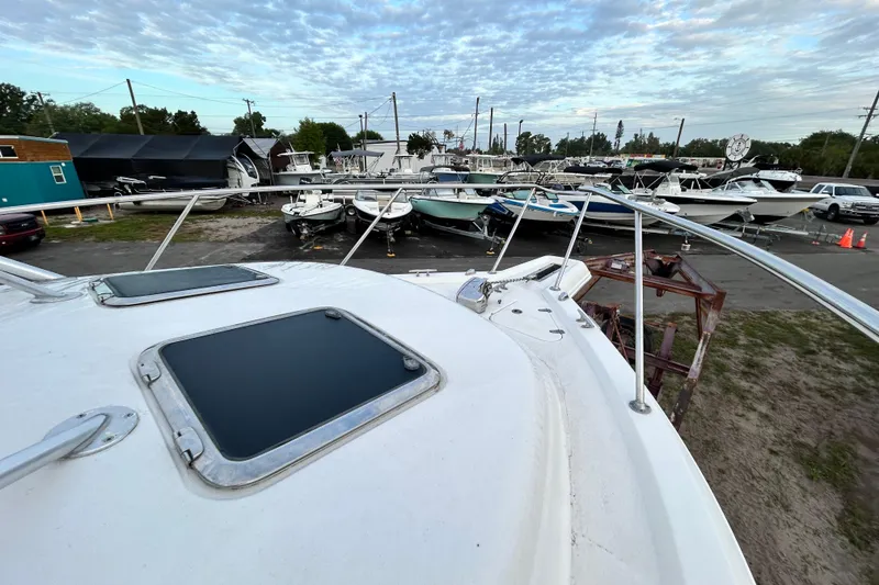 Slide: The Image of 2007 Pro-Line 32 Express boat in a marina with multiple vessels under a cloudy sky. - 65
