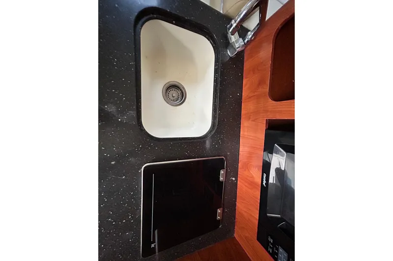 Slide: The Image of 2007 Pro-Line 32 Express boat kitchen with sink, black countertop, and wooden cabinetry. - 89