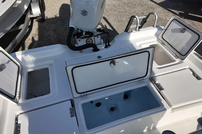 Slide: The Image of 2026 Blazer PureBay 2400 boat deck with open storage compartments and motor. - 11