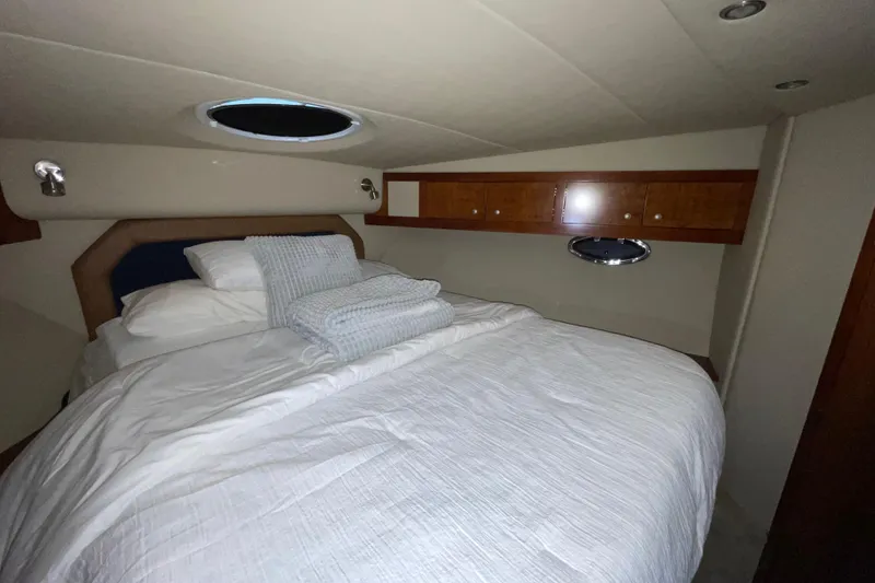 Slide: The Image of 2008 CRUISERS INC 415 Express Motoryacht bedroom with cozy bedding and wooden storage cabinets. - 22