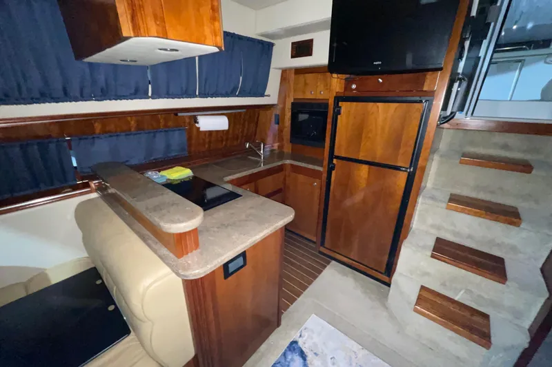 Slide: The Image of 2008 CRUISERS INC 415 Express Motoryacht interior with kitchen, wooden cabinetry, and stairs. - 27
