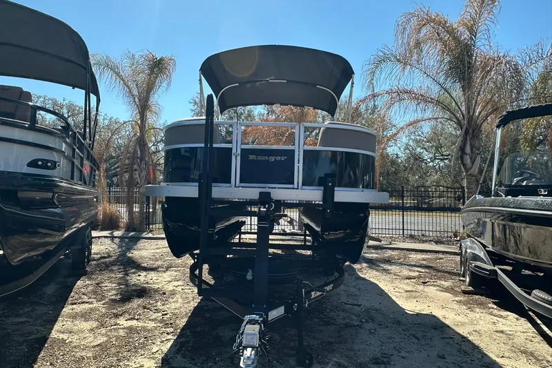 Slide: The Image of 2024 Ranger Reata 200C pontoon boat on trailer, surrounded by palm trees. - 2