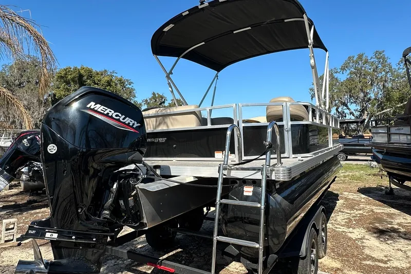 Slide: The Image of 2024 Ranger Reata 200C pontoon boat with Mercury outboard engine, parked outdoors. - 30