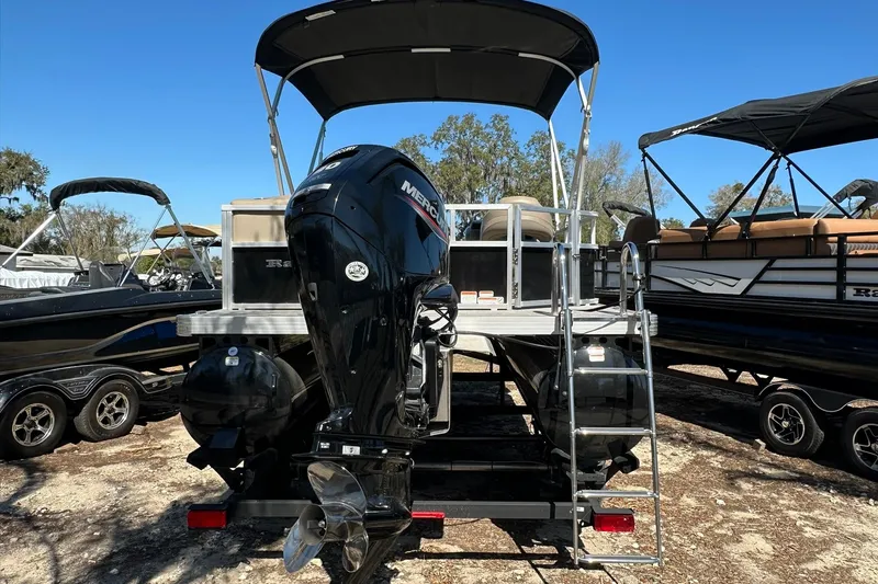 Slide: The Image of 2024 Ranger Reata 200C pontoon boat with Mercury outboard motor, parked on a trailer. - 32