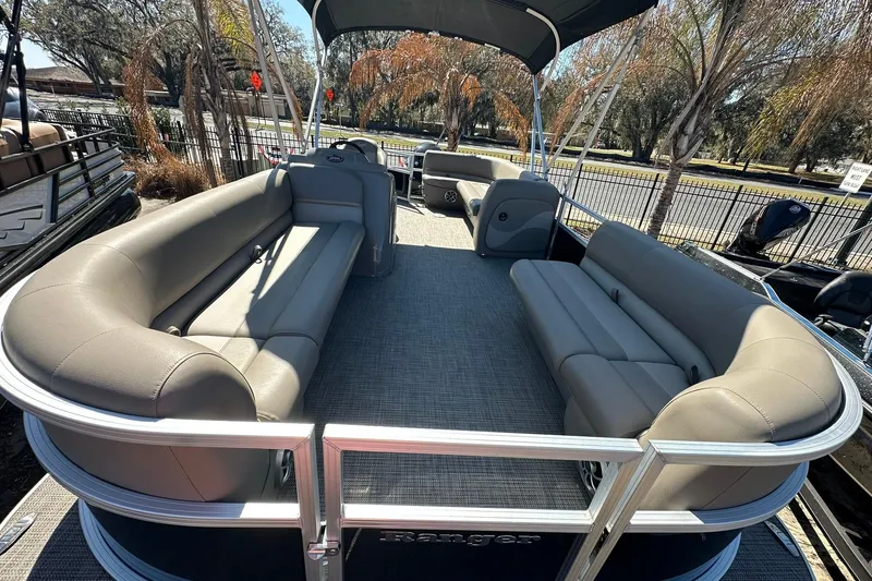 Slide: The Image of 2024 Ranger Reata 200C pontoon boat with spacious seating and canopy, parked outdoors. - 4