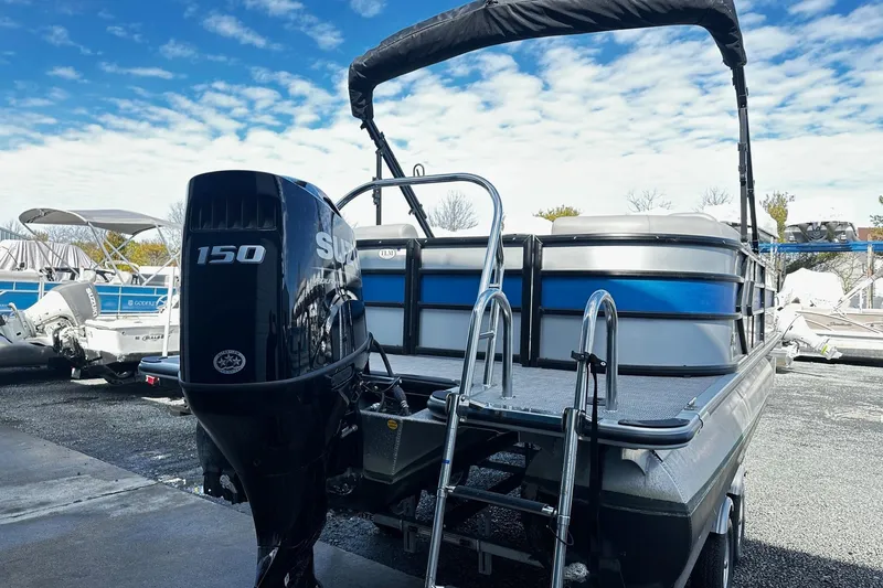 Slide: The Image of 2025 Bentley 223 Bolt Tri Toon boat with Suzuki 150 outboard motor, docked under a blue sky. - 10