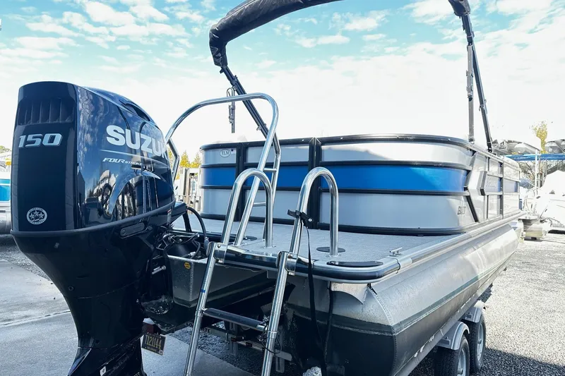 Slide: The Image of 2025 Bentley 223 Bolt Tri Toon with Suzuki 150 engine, docked under clear sky. - 2