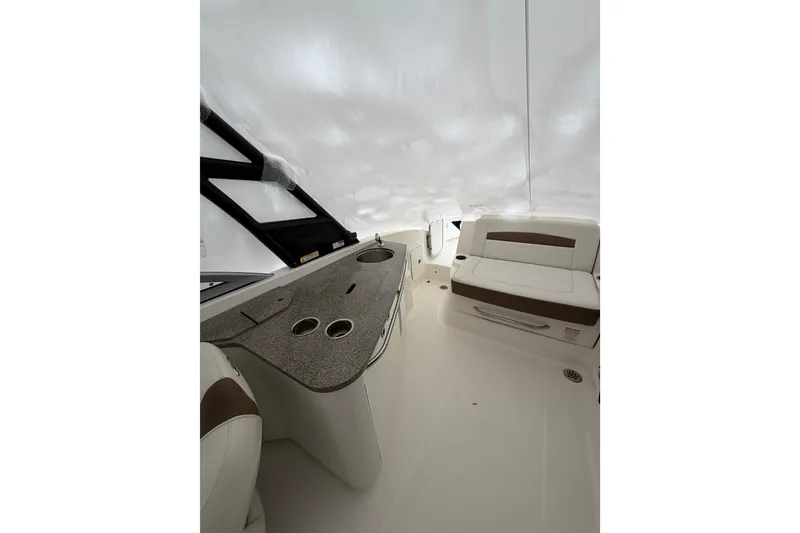 Slide: The Image of 2016 Chaparral 264 Sunesta boat interior with white and brown seating and helm. - 11