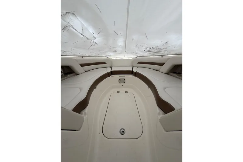 Slide: The Image of 2016 Chaparral 264 Sunesta boat interior with white seating and table on a lake. - 7