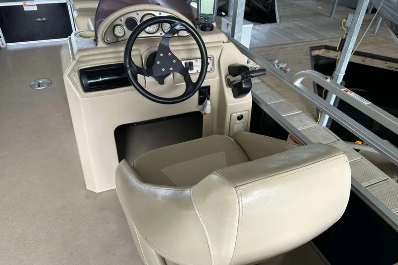 Slide: The Image of 2013 SunCatcher V322 RC boat helm with steering wheel and beige captain's chair. - 2