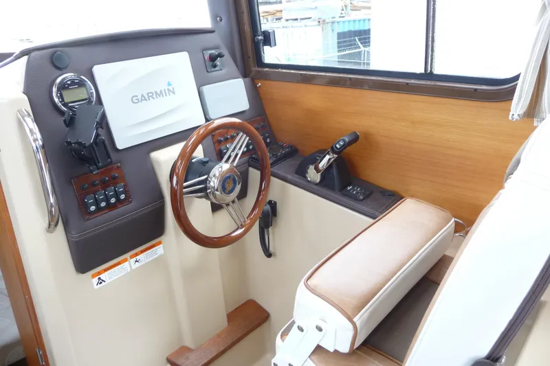 Slide: The Image of 2017 Ranger Tugs R-23 helm with Garmin navigation, wood accents, and leather seating. - 11