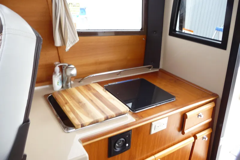 Slide: The Image of 2017 Ranger Tugs R-23 interior kitchen with wooden cabinetry and countertop. - 18