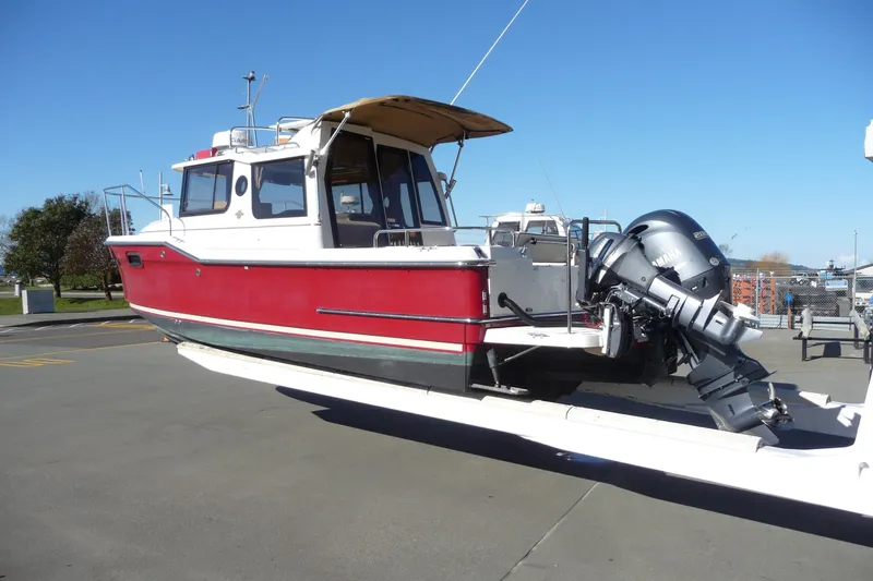 Slide: The Image of 2017 Ranger Tugs R-23 boat with outboard motor on trailer, red and white exterior. - 2