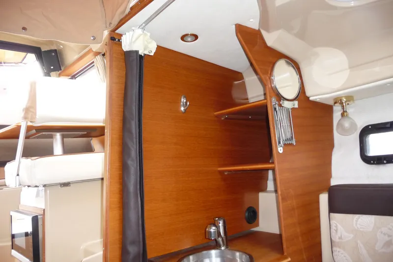 Slide: The Image of 2017 Ranger Tugs R-23 interior with wooden cabinetry, sink, and seating area. - 22