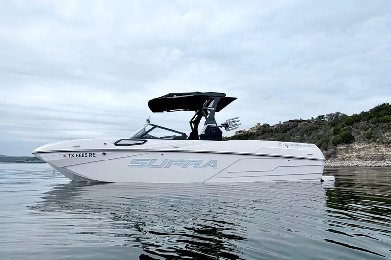 Slide: The Image of 2023 Supra SE 550 boat on calm water, overcast sky, scenic background. - 0
