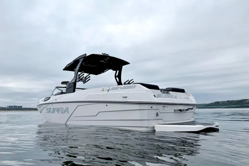 Slide: The Image of 2023 Supra SE 550 boat on calm water under cloudy sky. - 1