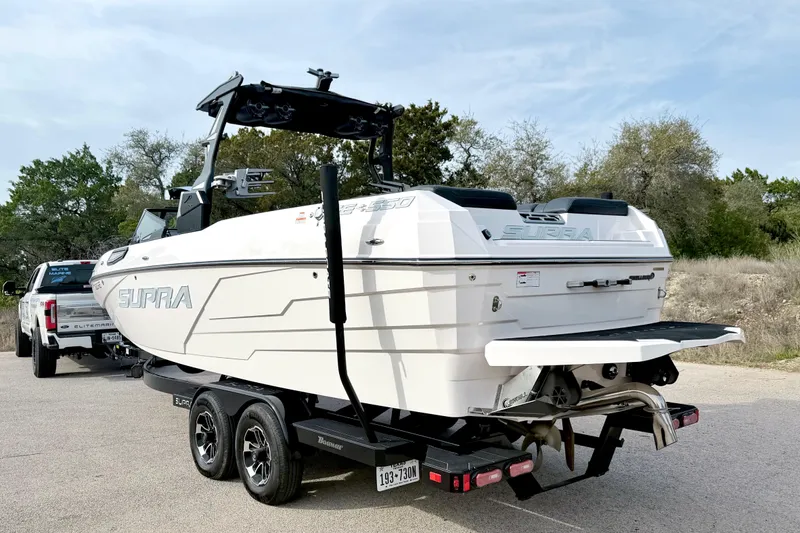 Slide: The Image of 2023 Supra SE 550 boat on trailer, parked outdoors, ready for transport. - 12