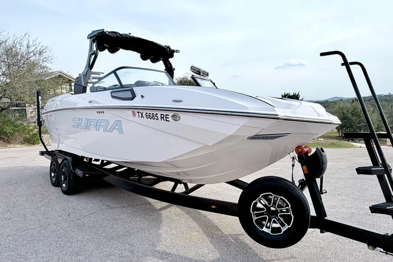 Slide: The Image of 2023 Supra SE 550 boat on trailer, sleek design, white exterior, parked outdoors. - 15