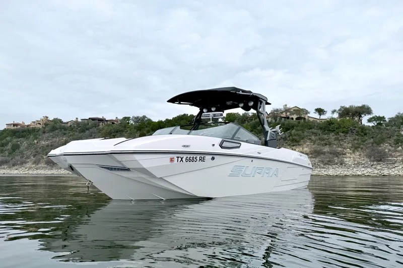 Slide: The Image of 2023 Supra SE 550 boat on calm water, with scenic shoreline background. - 2