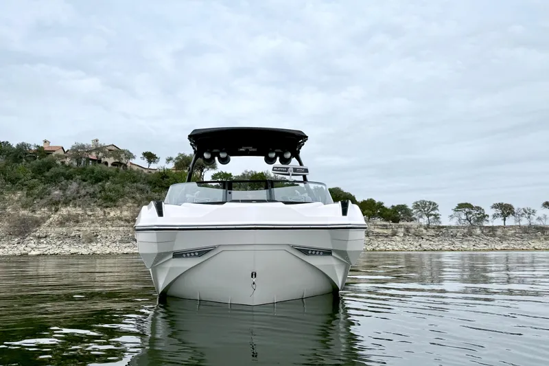 Slide: The Image of 2023 Supra SE 550 boat on calm water with scenic shoreline background. - 6