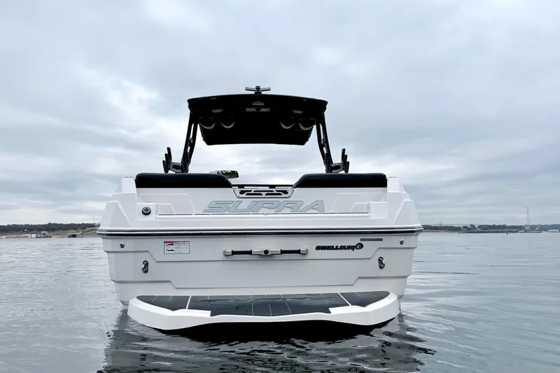 Slide: The Image of 2023 Supra SE 550 boat on calm water, rear view, overcast sky. - 7