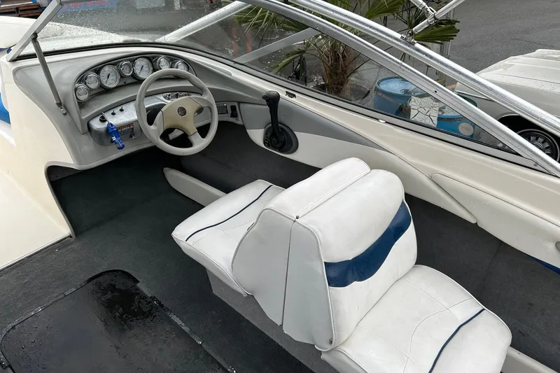 Slide: The Image of 2004 Bayliner 205 boat interior with steering wheel and white seating. - 10