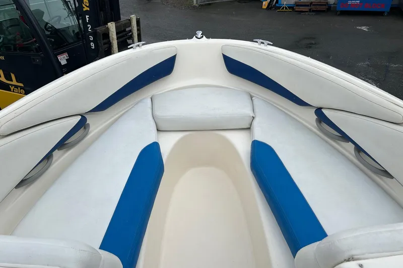 Slide: The Image of 2004 Bayliner 205 boat interior with white and blue seating, docked outdoors. - 9