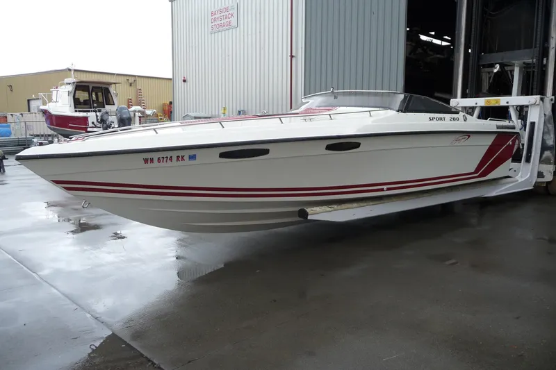 Slide: The Image of 1989 Baja 280 Sportfish boat with red accents on a lift at a marina. - 11