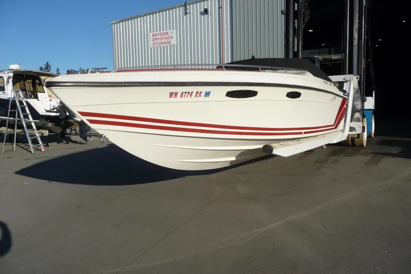 Slide: The Image of 1989 Baja 280 Sportfish boat with red stripes, parked near storage facility. - 3