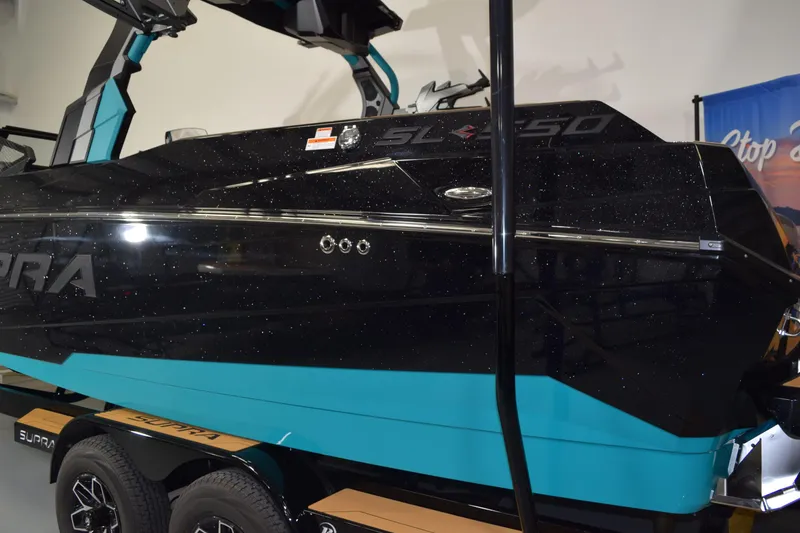 Slide: The Image of 2026 Supra SL 550 boat with sleek black and turquoise design on trailer. - 3