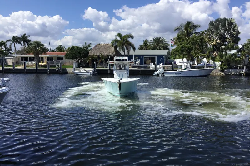 Slide: The Image of 2000 Jupiter 31 Center Console boat navigating a scenic waterfront with palm trees and docks. - 3