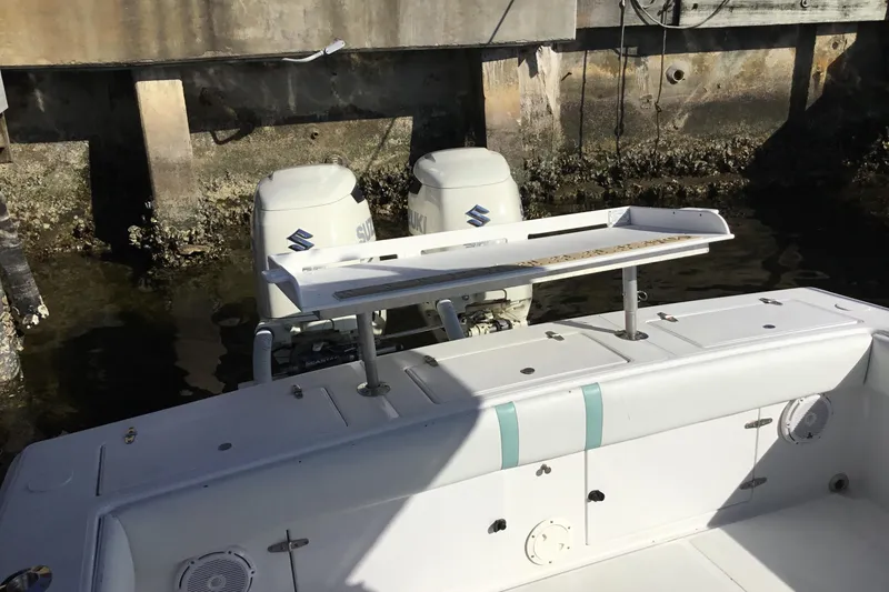 Slide: The Image of 2000 Jupiter 31 Center Console boat with dual Suzuki outboard engines docked by a concrete wall. - 35