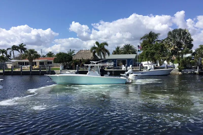 Slide: The Image of 2000 Jupiter 31 Center Console boat cruising on a sunny waterfront with palm trees. - 5