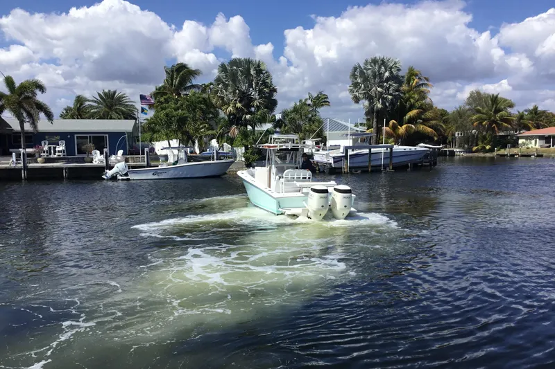 Slide: The Image of 2000 Jupiter 31 Center Console boat navigating a scenic waterfront with palm trees. - 66
