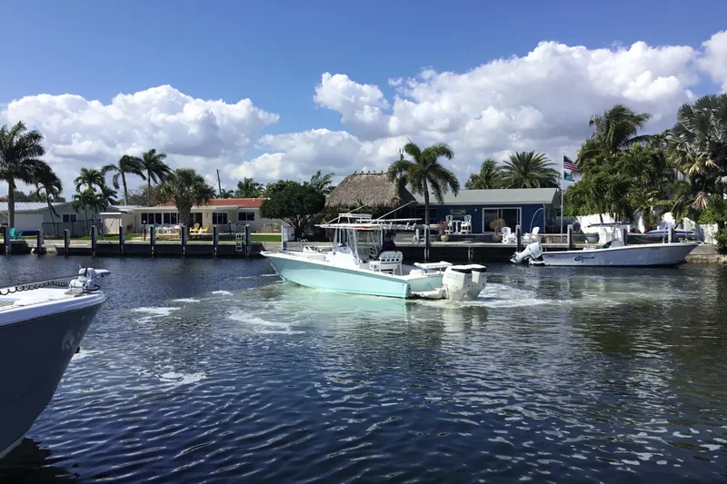 Slide: The Image of 2000 Jupiter 31 Center Console boat cruising on a sunny waterfront with palm trees. - 71