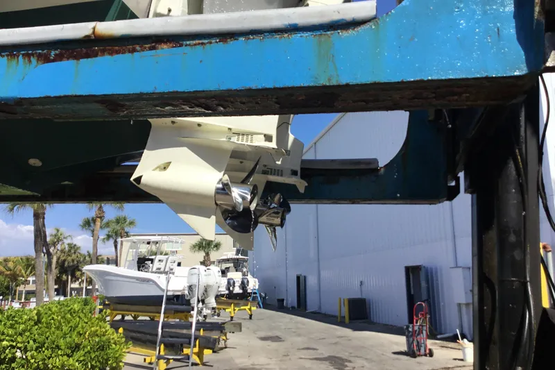Slide: The Image of 2000 Jupiter 31 Center Console boat on lift, showcasing propeller and marina background. - 72
