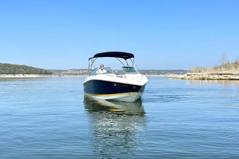 Slide: The Image of 2007 Cobalt 232 boat cruising on a calm lake under a clear blue sky. - 11