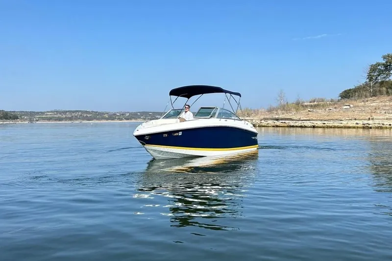 Slide: The Image of 2007 Cobalt 232 boat cruising on a calm lake under a clear blue sky. - 12